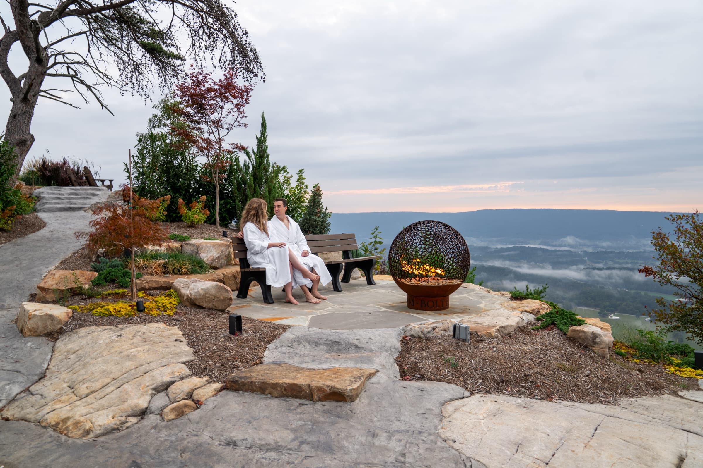 A couple by the fire at the mountaintop overlook at dusk