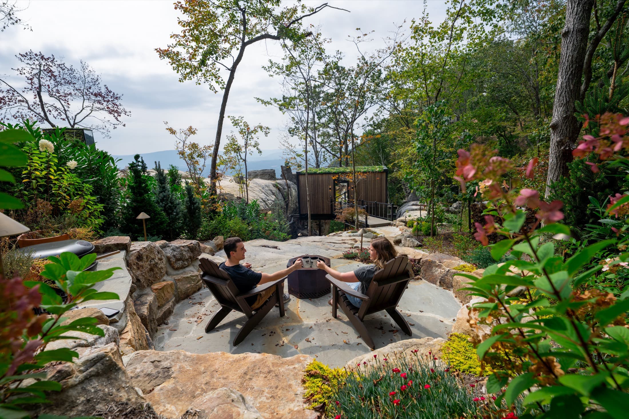 A couple toasting by the fire pit outside a BOLT FARM mirror cabin